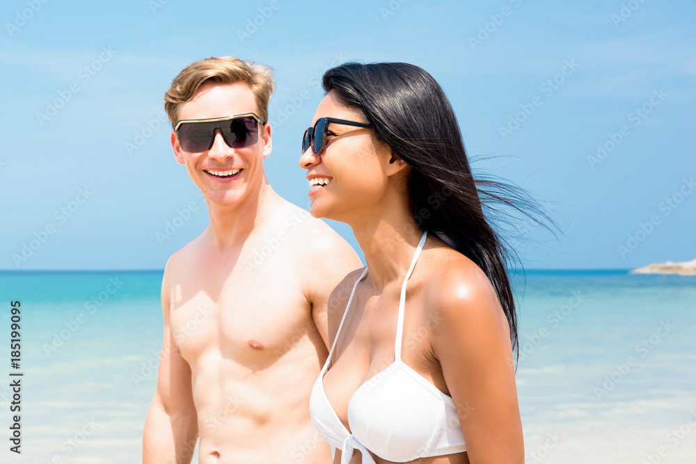 Young interracial tourist couple strolling along the beach Young interracial tourist couple strolling along the beach