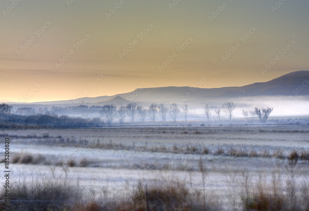 EDGE OF DARKNESS. Mist hangs low over farmlands in the Umzimkulu Valley, Underberg, Kwazulu Natal, South Africa EDGE OF DARKNESS. Mist hangs low over farmlands in the Umzimkulu Valley, Underberg, Kwazulu Natal, South Africa