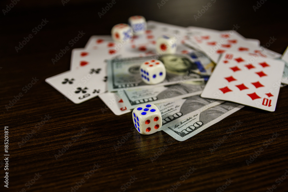 Playing cards, dice and one hundred dollar bills on a dark wooden table Playing cards, dice and one hundred dollar bills on a dark wooden table