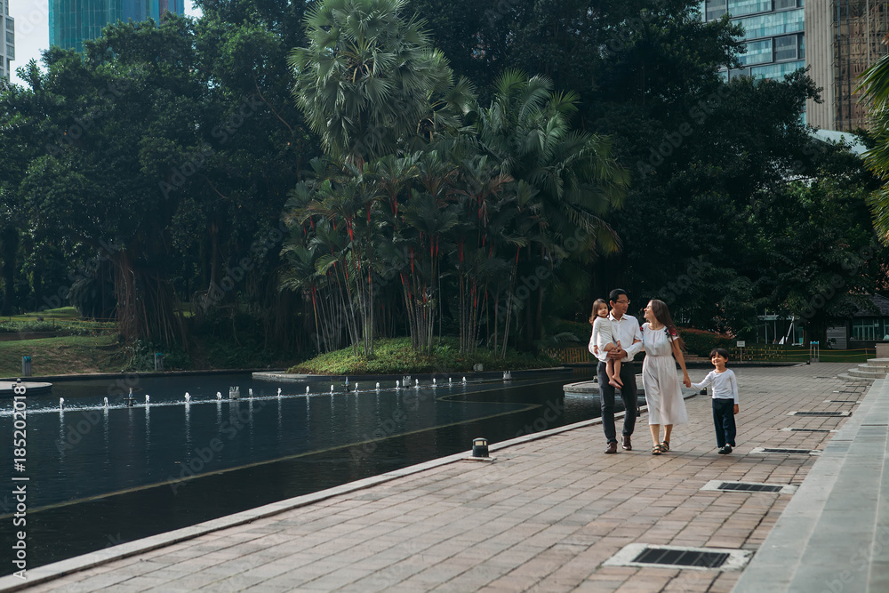 happy stylish parents holding hands with son and daughter walking in sunny street, amazing family moment. father's mother's day happy stylish parents holding hands with son and daughter walking in sunny street, amazing family moment. father's mother's day
