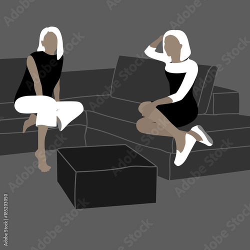 Two yang woman sitting on the modern gray sofa.