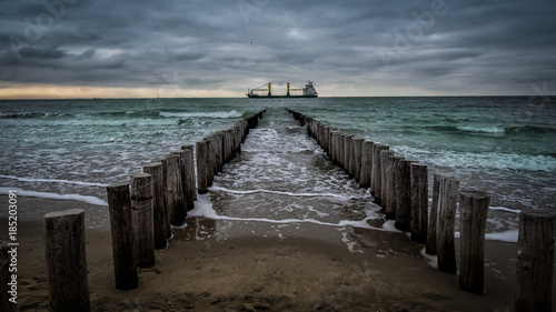Big ship crossing the wooden pier during cloudy weather at the beach in Vlissingen  Zeeland  Holland  Netherlands