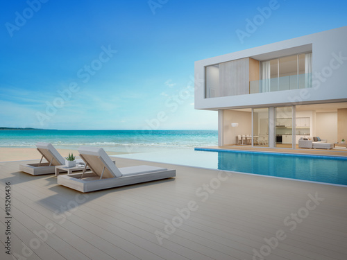Luxury beach house with sea view swimming pool and terrace in modern design, Lounge chairs on wooden floor deck at vacation home or hotel - 3d illustration of contemporary holiday villa exterior © terng99