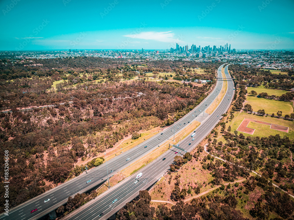 Aerial panorama of highway leading to Melbourne downtown skyscrapers on hot summer day