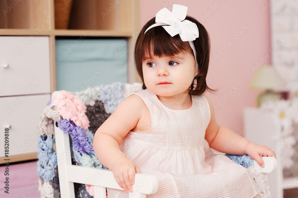 cute happy 1 year old baby girl playing with wooden toys at home. Modern nursery interior, early learning concept