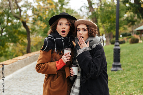 Portrait of two shocked girls dressed in autumn clothes