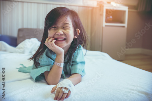 Illness asian child admitted in hospital with saline iv drip on hand.