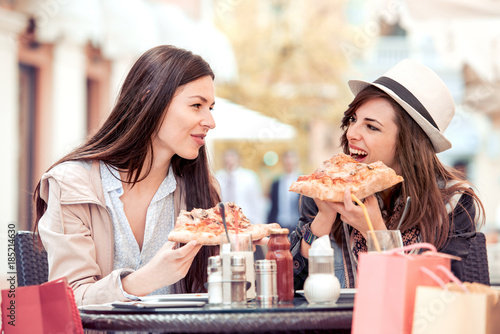 Portrait of happy young female friends eating pizza.