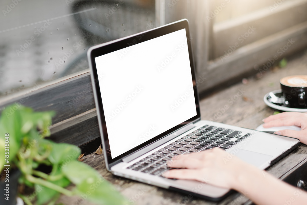 Mockup image of business woman using and typing on laptop with blank white screen and coffee cup on glass table in modern loft cafe, Soft focus on vintage wooden table. Mockup image of business woman using and typing on laptop with blank white screen and coffee cup on glass table in modern loft cafe, Soft focus on vintage wooden table.