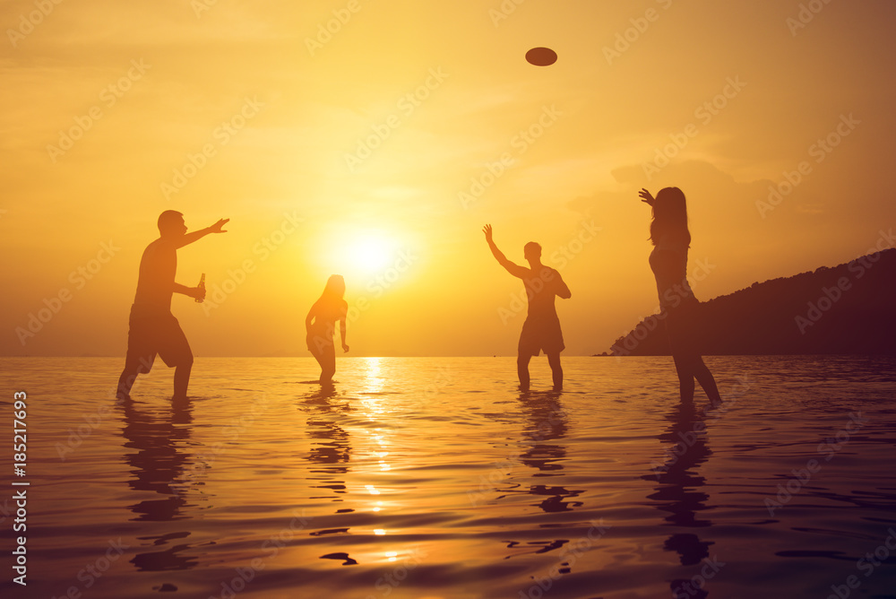 Silhouette of people playing at the beach in summer sunset