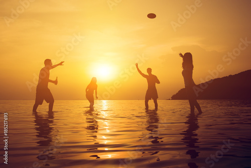 Silhouette of people playing at the beach in summer sunset