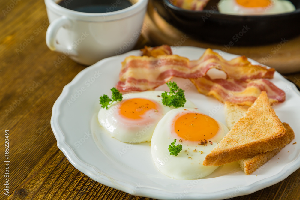 American breakfast with sunny side up eggs, bacon, toast, pancakes, coffee and juice American breakfast with sunny side up eggs, bacon, toast, pancakes, coffee and juice