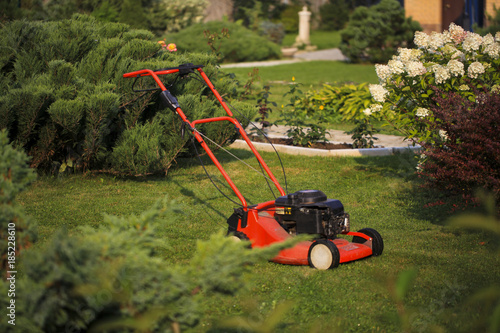 Blurred background of the home garden and lawn mower on mown grass.