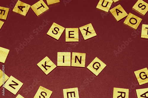 Wooden blocks on a red background spelling words Sex King. Art style