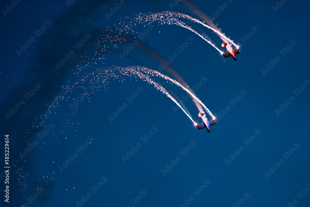 Two planes on the sky during the night airshow. - obrazy, fototapety, plakaty 