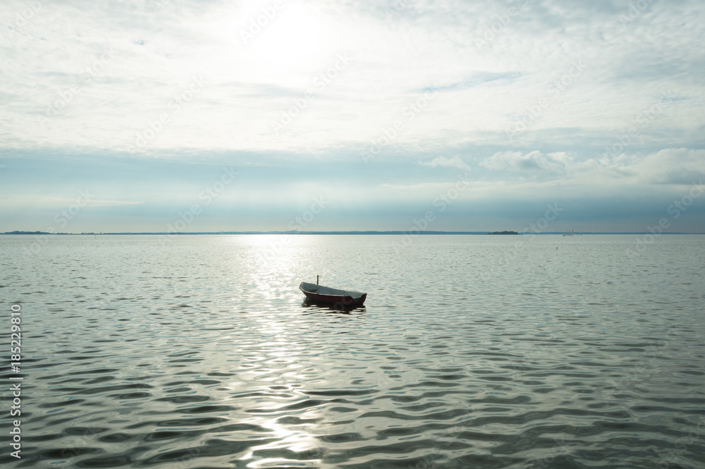 Naklejka premium Alone boat on Denmark fyord on sea with cloudy sky