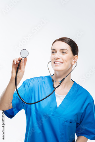 Where pain. Elegant attractive female doctor holding stethoscope while diagnosing people and posing on the white background