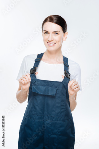 Time to work. Cheerful gorgeous female architect drawing back  coveralls while considering and smiling to the camera photo