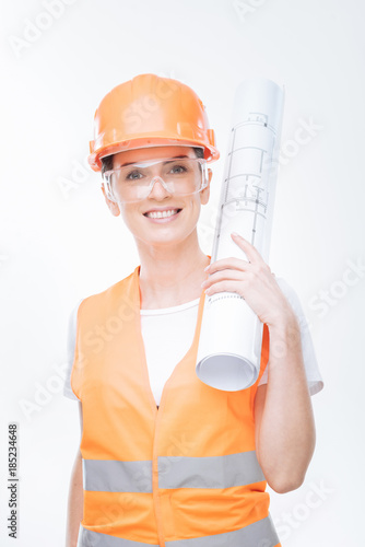 Architectural ideas. Creative vigorous female architect grinning  and placing blueprint on the shoulder while posing on the white background photo