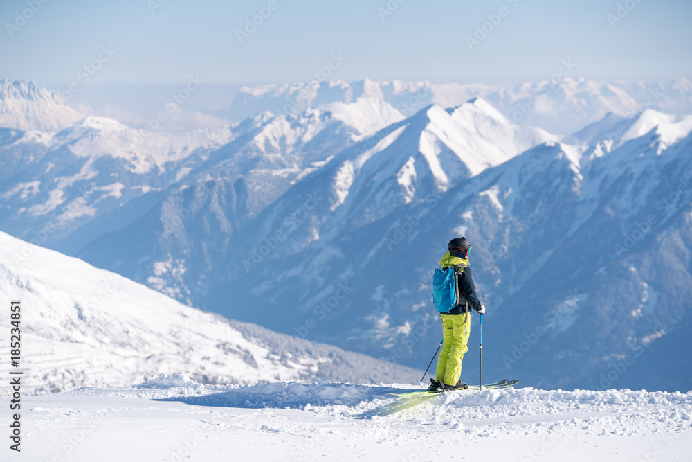 Hiker with skis looking at a view while standing on a mountain Hiker with skis looking at a view while standing on a mountain