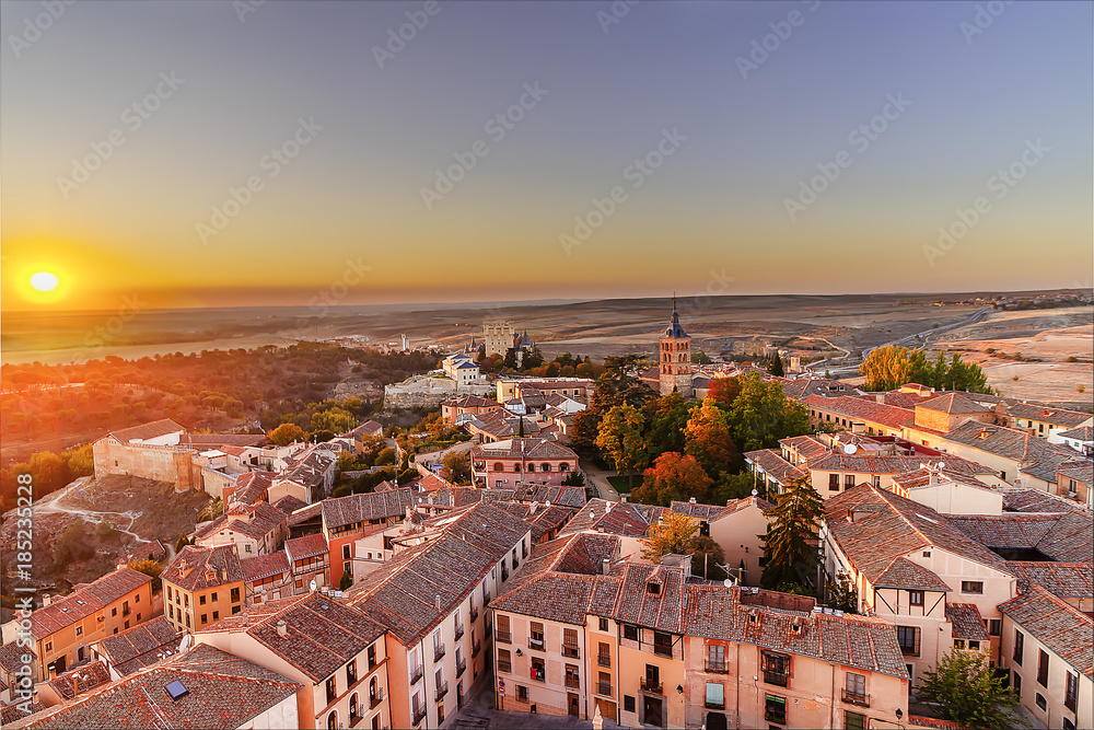 Aerial view of Segovia at sunset in autonomous region of Castile and León, with illuminated buildings and Alcazar. Castle residence of kings in medieval epoch,