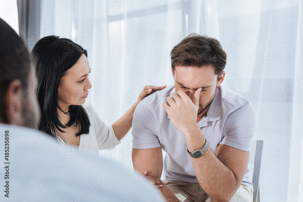 Obraz premium selective focus of mature asian woman supporting crying man during group therapy