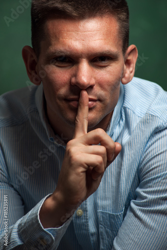Portrait of Handsome sensual man holding finger on his mouth
