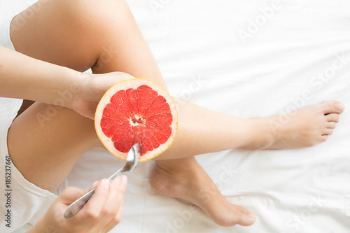 Healthy eating concept. Woman having grapefruit in bed. Top view.
