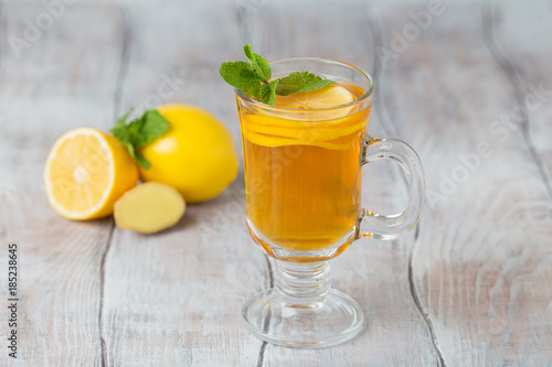 Lemon ginger tea in glass with mint and honey on a white background.  Close-up.