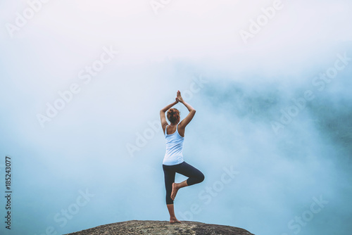 Asian women relax in the holiday. Play if yoga. On the Moutain rock cliff. Nature of mountain forests in Thailand