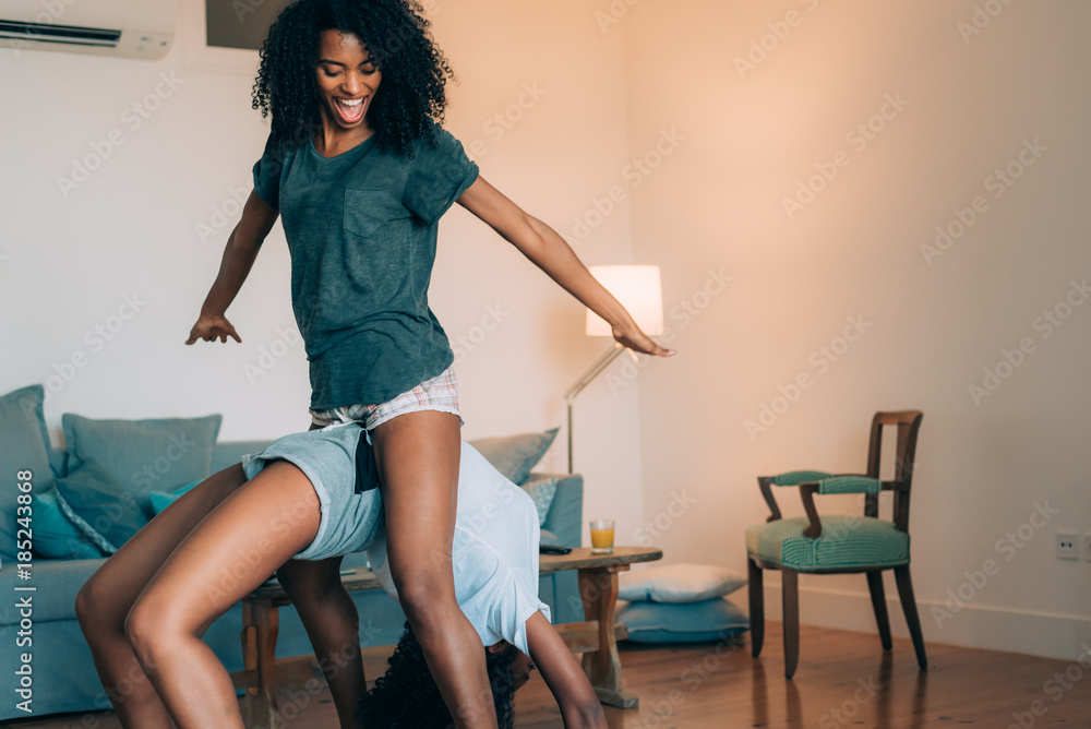 Fototapeta premium Happy young two black women relaxed at home playing .