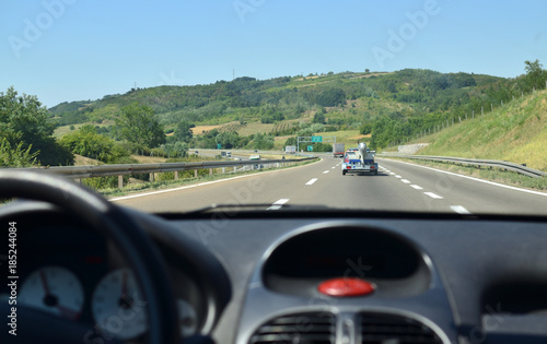 Man driving a car on a highway with other vehicles blurred in front of him and a road block with a redirection sign