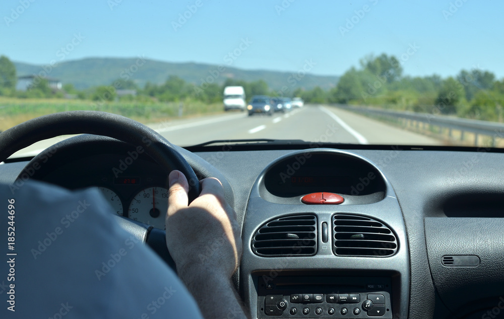 Man driving a car on a highway in traffic jam time and with other vehicles blurred next his car