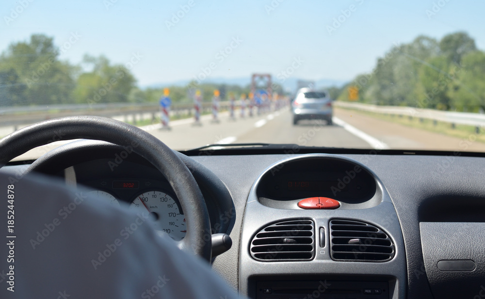 Man driving a car with other vehicles blurred in front of him and a road signaling