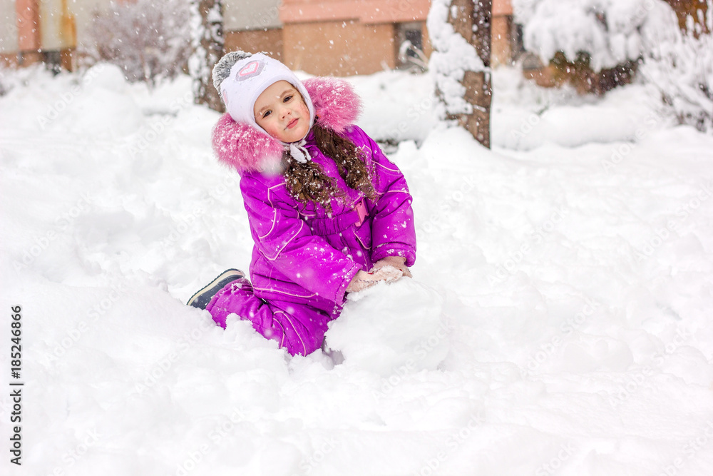 Little kid girl builds snowman on winter day outdoors. Little kid girl builds snowman on winter day outdoors.
