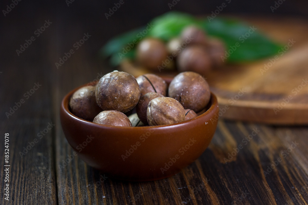 Obraz premium Brown ceramic bowl with macadamia nuts inside.