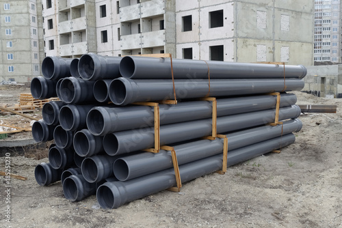 Close up of rubber pipes on pile and other construction material and equipment at building site photo