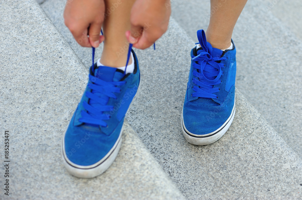 young woman hands tying shoelace on city stairs