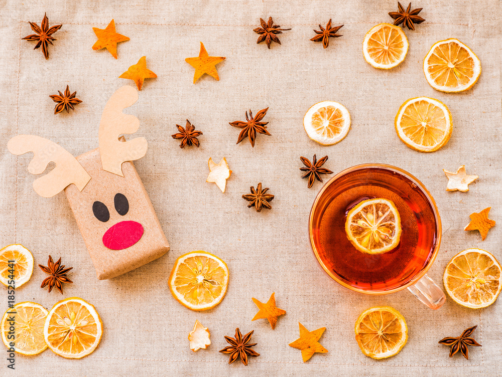 ecological deer craft from recycled paper on linen background with cup of hot tea, lemons, oranges and decorations ecological deer craft from recycled paper on linen background with cup of hot tea, lemons, oranges and decorations