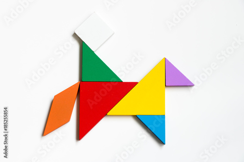 Colorful wood tangram puzzle in man riding horse shape on white background