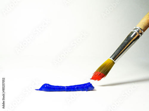 A strip of blue paint and a brush with red paint.