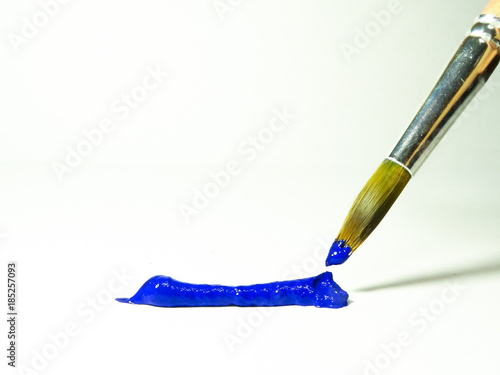 Blue acrylic paint on the brush and on a sheet of paper.