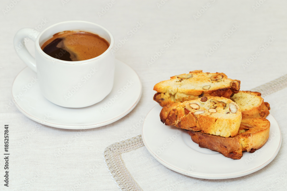 Italian homemade biscotti with nuts on white plate on tablecloth of fabric. Cantucci and coffee for breakfast. Selective focus. Copy space. Italian homemade biscotti with nuts on white plate on tablecloth of fabric. Cantucci and coffee for breakfast. Selective focus. Copy space.