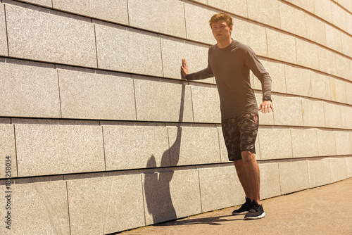 Young male jogger athlete training and doing workout outdoors in city.