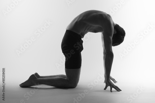 Young attractive man shows poses in yoga