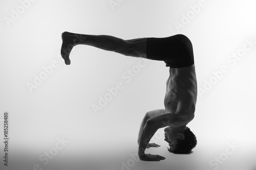 Young attractive man shows poses in yoga