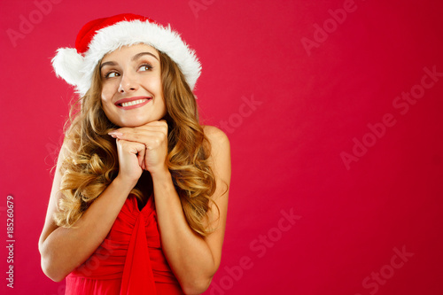 Young attractive Santa girl in red dress over red background