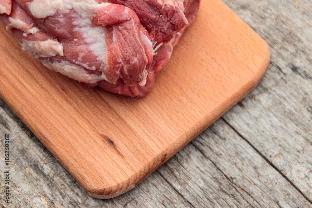 Raw pork meat on cutting board on a table Raw pork meat on cutting board on a table