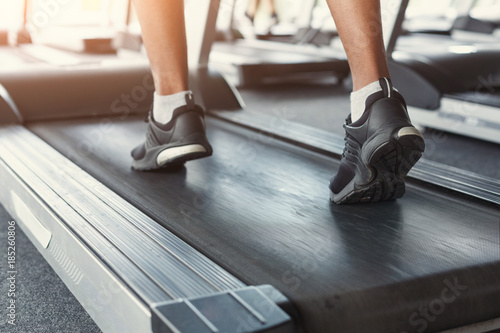 Man's feet on treadmill in fitness club, healthy lifestyle