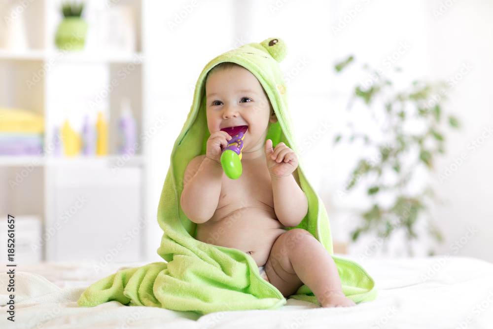 Little baby in green towel biting toy after bath. Infant boy with teether. Child health care. Little baby in green towel biting toy after bath. Infant boy with teether. Child health care.
